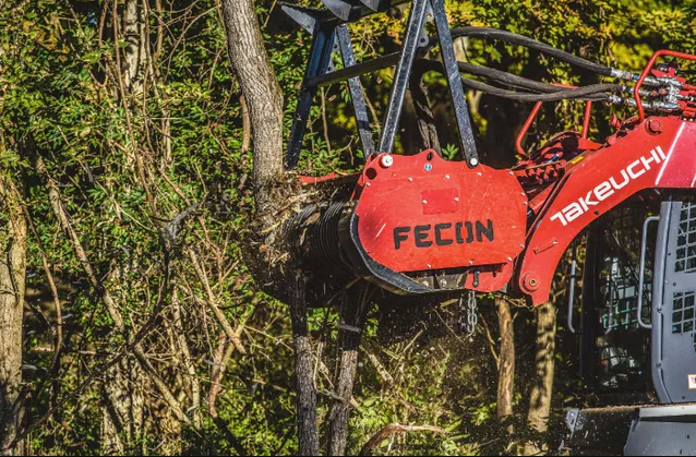 a red tractor is parked in a wooded area